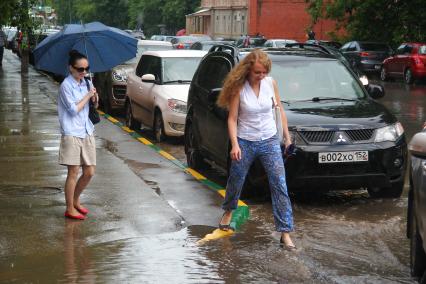 Нижний Новгород. Женщина переходит через глубокую лужу во время сильного дождя.