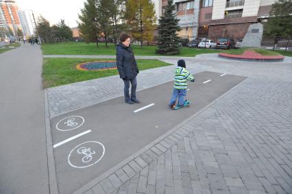 Москва.  Ребенок едет на самокате по велодорожке  длиной три метра, на улице Удальцова.