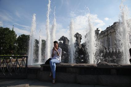 Москва. Девушка сидит возле скульптурной группы `Времена Года` фонтана `Гейзер`.
