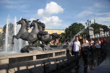 Москва. Люди идут мимо скульптурной группы `Времена Года` фонтана `Гейзер`.
