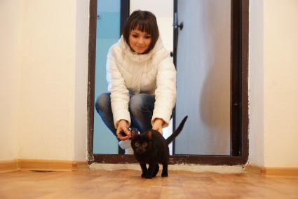 Свердловская область, г. Серов. Девушка запускает кошку в свою квартиру в новом доме, полученную по программе `Доступное жилье` для молодых семей.