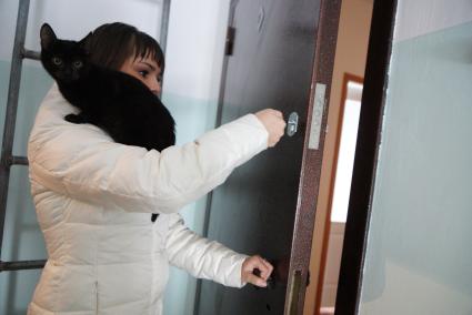 Свердловская область, г. Серов. Девушка открывает дверь своей квартиры в новом доме, полученной по программе `Доступное жилье` для молодых семей.