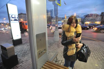 Москва.   Первая `умная` остановка  на Садовом кольце, около Театра кукол им. Образцова.  Девушка заряжает мобильный телефон.