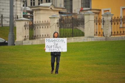 Москва.  Активист  Валентин Карелин держит плакат  `Мединский ты портишь город!` во время одиночного пикета рядом с местом  установки памятника святому равноапостольному князю Владимиру на Боровицкой площади.