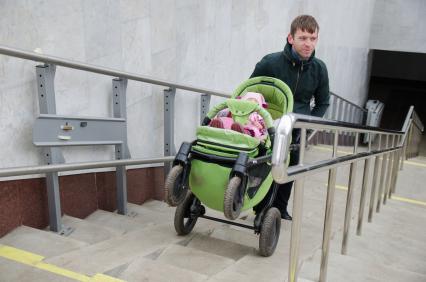 Самара. Мужчина поднимает по лестнице детскую коляску с помощью пандуса.