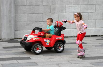 Владивосток. Дети катаются по набережной на роликах и детской машинке.