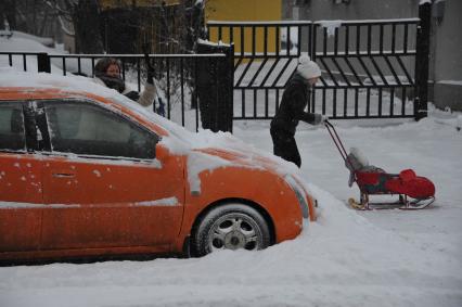 Москва. Женщина чистит автомобиль от снега.