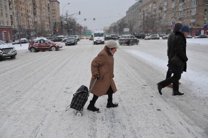 Москва. Люди переходят заснеженную дорогу.