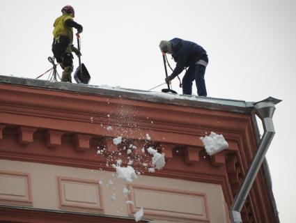 Москва. Сотрудники коммунальной службы счищают снег с крыши дома.