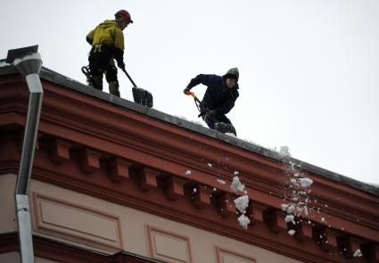 Москва. Сотрудники коммунальной службы счищают снег с крыши дома.