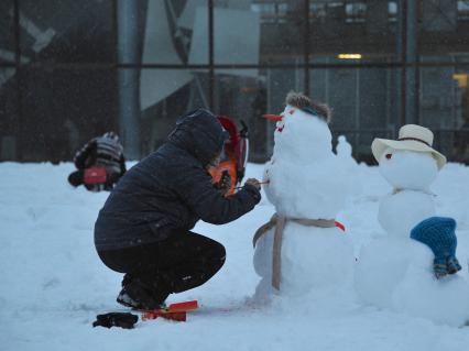 Москва. Женщина украшает снеговика.
