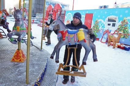 Екатеринбург. Рабочий устанавливает лошадку на карусель во время строительства ледового городка на `Площади 1905 года`.