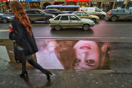 Москва.  Отражение девушки в луже на Новом Арбате.