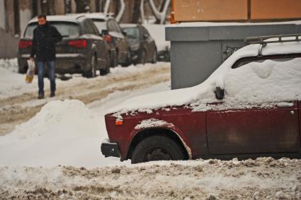 Последствия метели в Москве. Заснеженный автомобиль на неубранной улице.