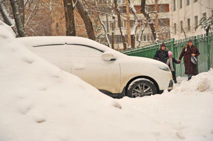 Последствия метели в Москве. Заснеженный автомобиль и сугробы.