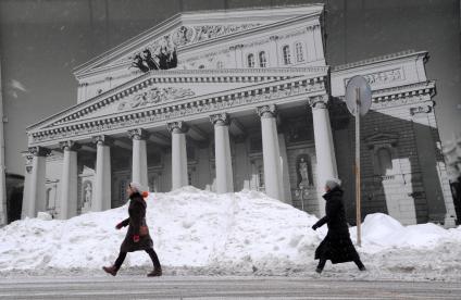 Москва. Люди идут мимо плаката с изображением Большого театра.