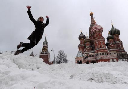 Москва. Девушка прыгает по сугробам на Красной площади.