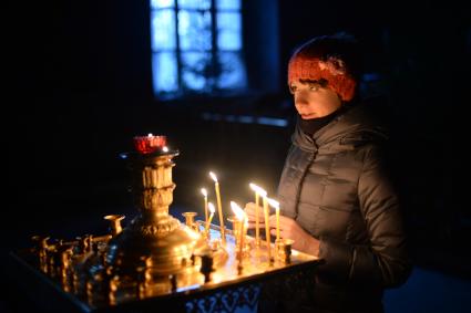 Калуга. Девушка ставит свечку в храме.
