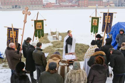 Крещенские купания в Санкт-Петербурге. Священнослужитель освящает прорубь в Неве.