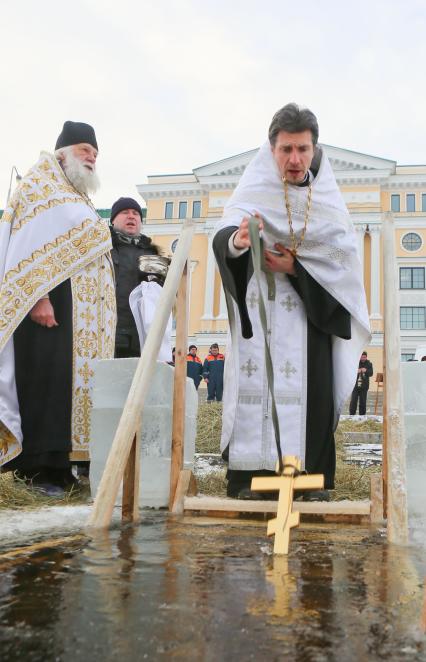 Крещенские купания в Санкт-Петербурге. Священнослужитель освящает прорубь в Неве.