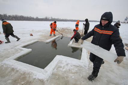 Подготовка к крещенским купаниям в Уфе. Рабочие режут лед в виде креста на месте купели в реке.