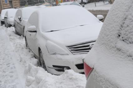 Москва.  Заснеженные автомобили на одной из улиц города.