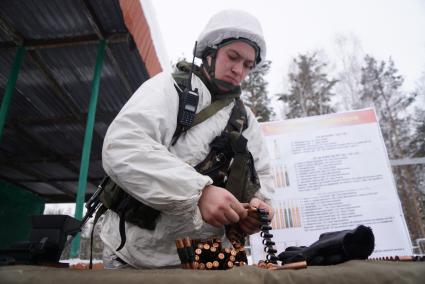 Свердловская область. Адуйский военный полигон. Военнослужащий мотострелковых войск заряжает пулеметную ленту в ходе проверки войск на способность слаженной работы между подразделениями.