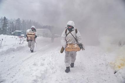 Свердловская область. Адуйский военный полигон. Военнослужащие мотострелковых войск несут ящики с боеприпасами проходя дымовую завесу в ходе проверки войск на способность слаженной работы между подразделениями.