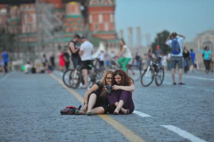 Москва. Девушки с фотокамерой сидят на Красной площади.