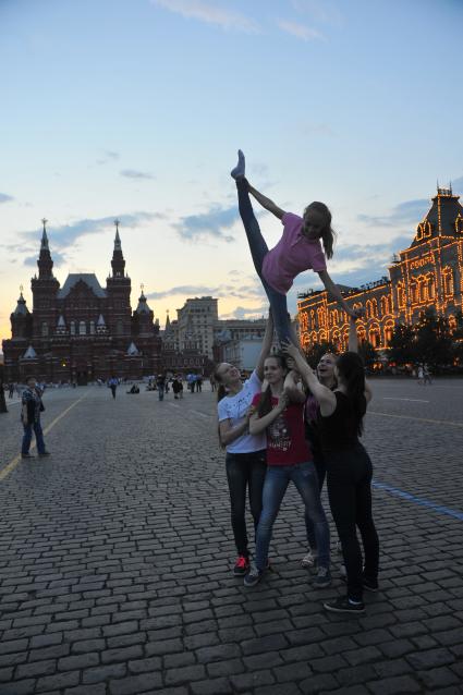 Москва. Группа девочек-гимнасток на Красной площади изображают акробатический элемент.