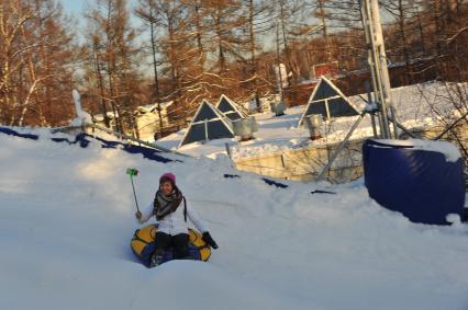 Москва. Девушка катается на тюбинге с горки в парке Сокольники.