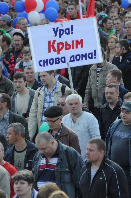 Москва. Участник традиционной первомайской демонстрации держит плакат `Ура! Крым снова дома!` во время шествия по Красной площади.