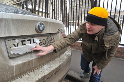 Москва. Корреспондент КП Олег Адамович снимает залепленный снег с номера автомобиля, припаркованного на платной стоянке.