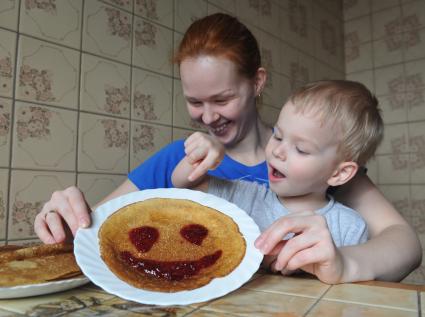 Москва. Девушка с ребенком демонстрируют блин со смайликом из варенья.