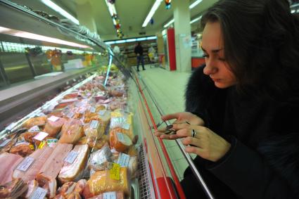 Москва.  Покупательница  у витрины с мясной продукцией в универсаме.