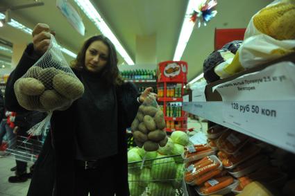 Москва. Покупательница выбирает картофель в овощном отделе универсама.
