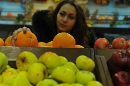 Москва.  Покупательница выбирает фрукты в универсаме.