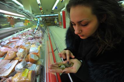 Москва.  Покупательница  у витрины с мясной продукцией в универсаме.