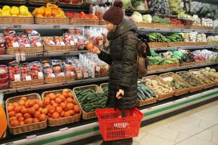 Нижний Новгород. Девушка выбирает овощи в супермаркете.