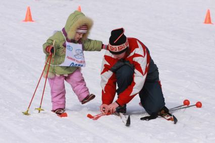 Барнаул. Женщина одевает лыжи ребенку.