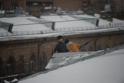 Москва. Сотрудники коммунальной службы счищают снег с крыши дома.