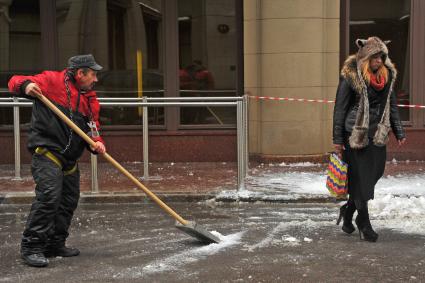 Москва.  Работник  коммунальной службы убирает снег на улице.