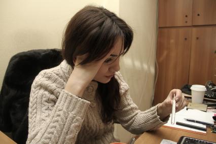 Нижний Новгород. Девушка на рабочем месте в офисе измеряет температуру.