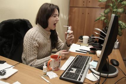 Нижний Новгород. Девушка на рабочем месте в офисе принимает лекарства от ангины.