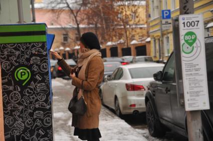 Москва.  Женщина оплачивает парковку автомобиля на одной из улиц города.