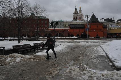 Москва.   Мужчина обходит лужи на Театральной площади.