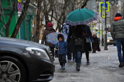 Москва.   Мама с ребенком под зонтиками.