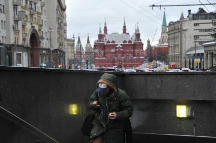 Москва.   Молодой человек с мобильным телефоном выходит из подземного перехода на Тверской улице.