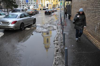Москва. Женщина идет по тротуару вдоль дороги.