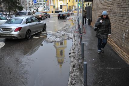 Москва.  Женщина идет по тротуару вдоль дороги.